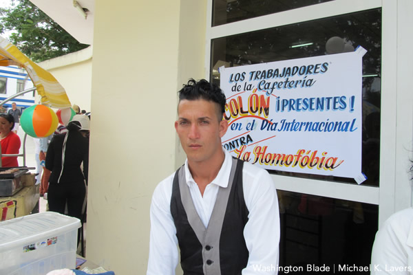 An man selling ice cream stands outside his café in Las Tunas, Cuba, on May 16, 2015. The sign behind him indicates support for the International Day Against Homophobia and Transphobia. (Washington Blade photo by Michael K. Lavers)