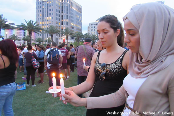 Two women hold candles outside the Dr. Phillips Performing Arts Center in Orlando, Fla., on June 13, 2016, during a memorial to the victims of the Pulse nightclub massacre. (Washington Blade photo by Michael K. Lavers)