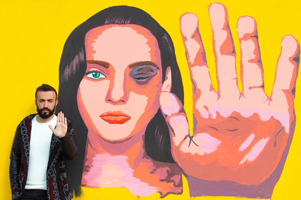 Ayaz Shalal of the Rasan Organization stands in front of a mural that calls for an end to domestic violence in the semi-autonomous Kurdish region of northern Iraq. (Photo courtesy of Capture Group/Zhyari)
